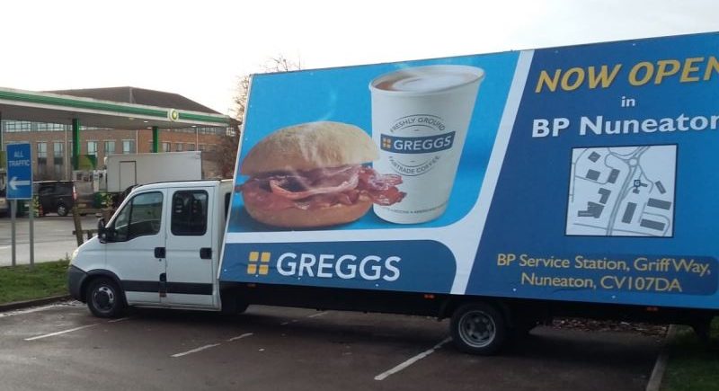 Greggs - Gorilla Media Greggs mobile ad van parked at a service station showing items from Greggs breakfast menu